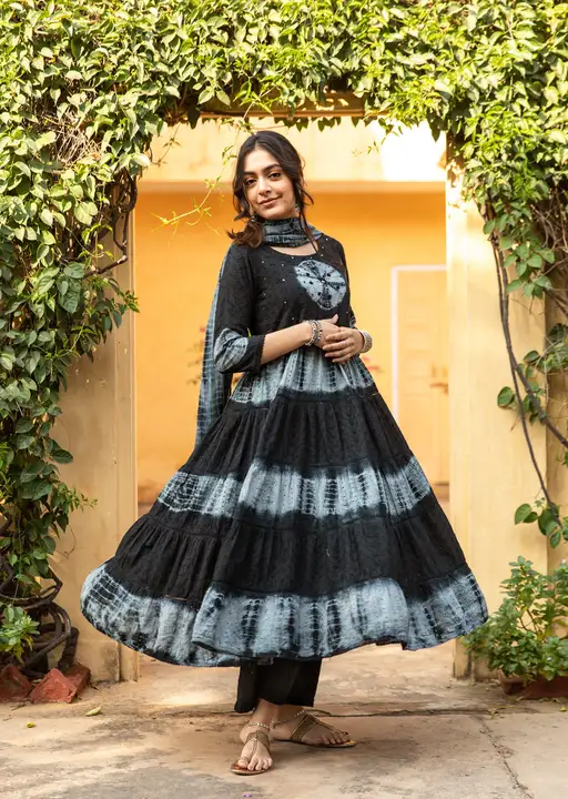 Post image Embrace your look with this elegant tiered kurta combo set along with a fancy potli. This black-colored kurta paired with a palazzo made up of cotton fabric with a cotton tie-dye dupatta. Flared kurta has a tie and dye print embellished with mirror, knots, and, schiffli work. The palazzo has a tie and dye print featuring schiffli work all over. Complete your look with mid-length heels or traditional mojaris and shine your ethnic look